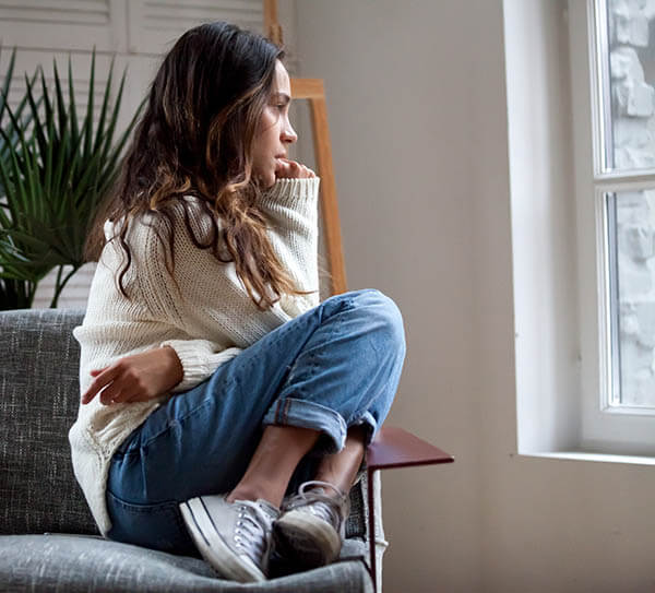 teen girl with anxiety sitting in chair, looking out window during anxiety therapy session