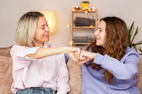 Happy mother and teenage daughter from Thousand Oaks, CA, enjoying a heartfelt conversation, reflecting the stronger family bonds nurtured through teen and parenting therapy