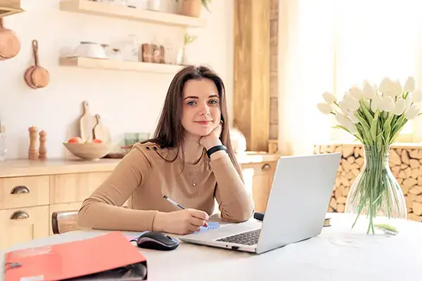 Happy teenage girl studying at home in Westlake Village, CA, illustrating improved academic focus and motivation resulting from effective teen therapy programs